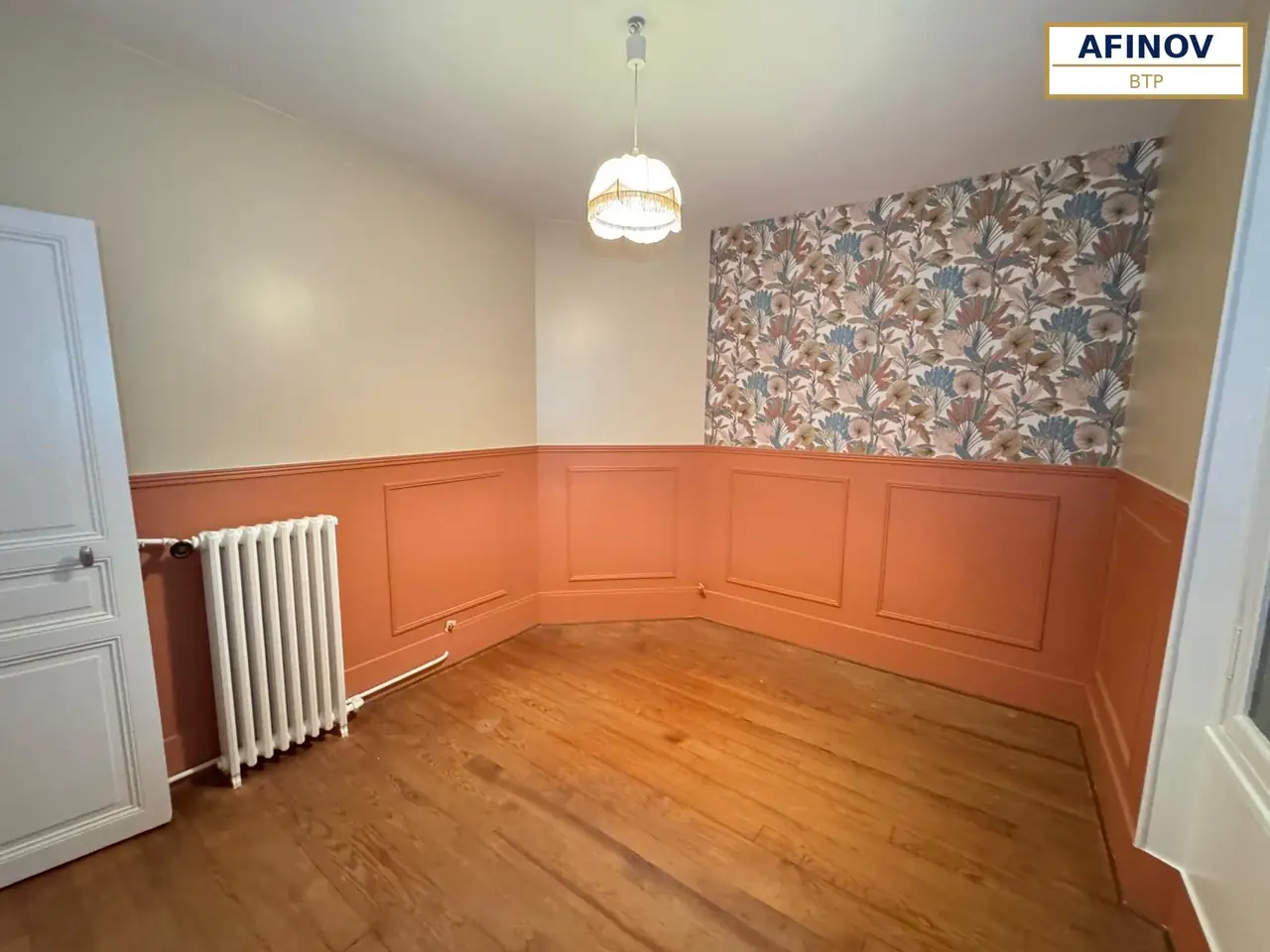 Pièce d’un appartement haussmannien rénové par Afinov BTP : lambris terracotta, parquet et papier peint
