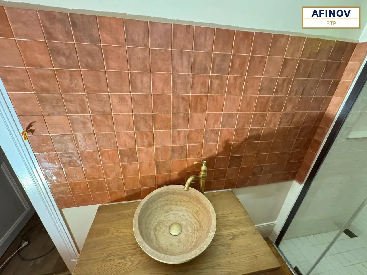 Salle de bain en carrelage terracotta et vasque en pierre, rénovée par Afinov BTP